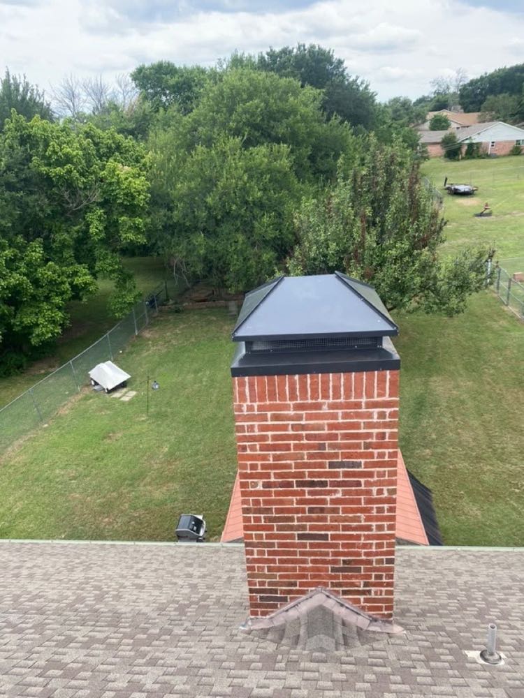 Red-brick chimney finished with a new black chimney cap in Dallas, TX