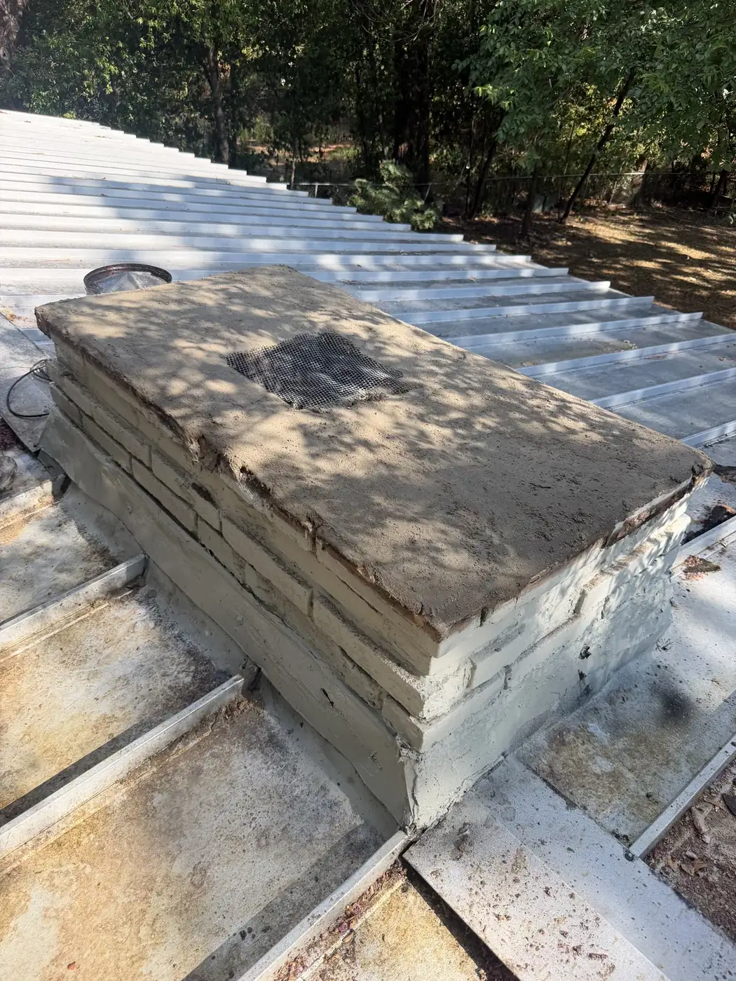 Uncapped chimney crown on a metal roof in North Texas