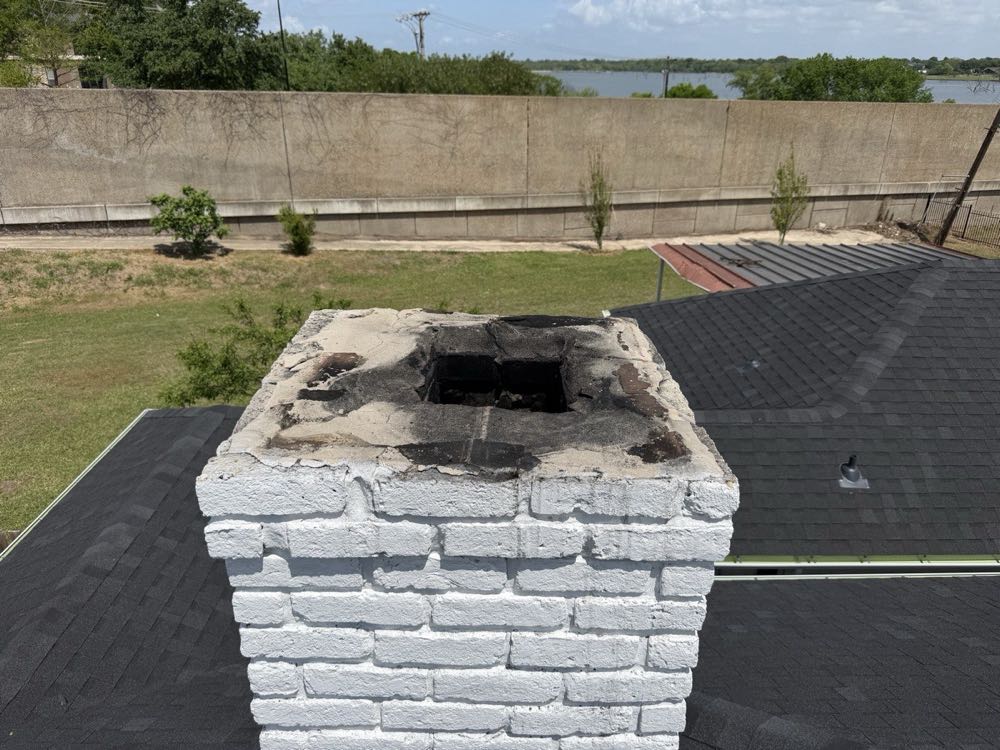 Texan Flue technician sweeping a white brick chimney from the rooftop in Dallas–Fort Worth
