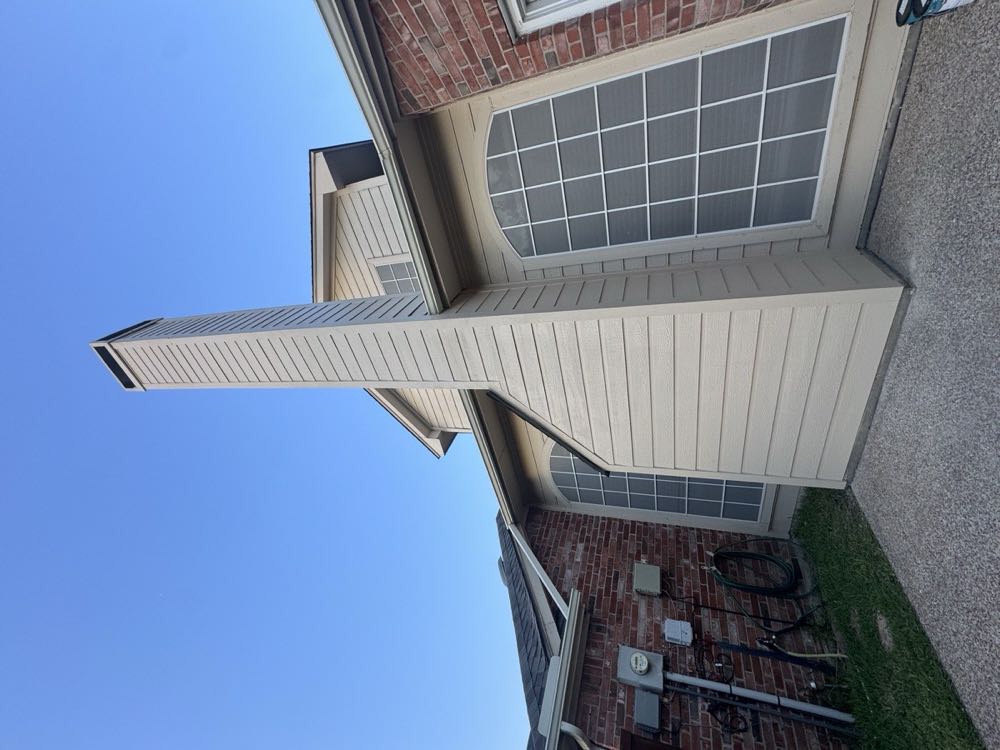 Chimney meeting the roofline of a North Texas home where a chimney cricket diverts rainwater